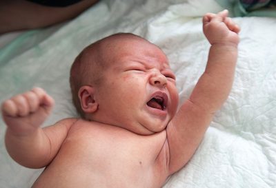 Overtired and overstimulated baby flails their arms and legs before sleep